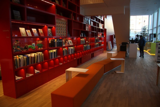 Red bookcase which goes from first to third floor